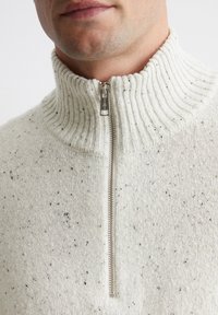 Helle graue Zip-Up-Cardigan mit geripptem Kragen, aus strukturiertem Strickstoff mit schwarzen und braunen Sprenkeln. Silberne Reißverschlussdetails.