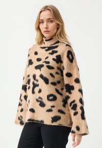 Bruine en zwarte luipaardprint trui met een hoge kraag, gemaakt van zacht, donzig materiaal, met brede mouwen en een relaxte pasvorm.