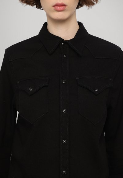 Camicia in denim nero con colletto, chiusura a bottoni e due tasche sul petto con pattina. Tessuto testurizzato con cuciture a contrasto.