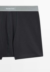 Černé bavlněné boxerky s šedým elastickým pasem označeným "Massimo Dutti" a kontrastními zelenými stehmi.