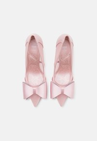 Chaussures à talons hauts roses avec un bout pointu, finition satinée et un grand nœud à l'avant. Comprend un design découpé et une semelle intérieure décorative.