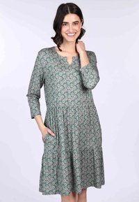 Blumenmuster-Kleid in Grün mit V-Ausschnitt, Dreiviertelärmeln und Taschen. Gestuftes Design mit lässiger Passform und weicher Stoffstruktur.