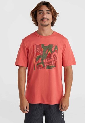 Camiseta de algodón de color coral con un gráfico cuadrado que presenta líneas de contorno verdes y rojas. Cuello redondo, mangas cortas y un corte relajado.