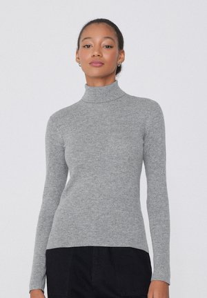 Grauer gerippter Rollkragenpullover mit langen Ärmeln, tailliertem Design und weicher Textur. Dazu werden dunkle Hosen mit schlanker Silhouette getragen.