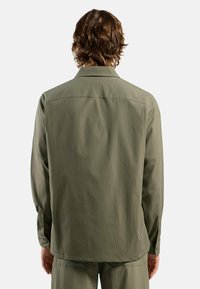 Olivgrünes Hemd, mittelschwerer Stoff, lange Ärmel, gerader Schnitt, geknöpfte Manschetten, Rückenpasse, minimalistisches Design.