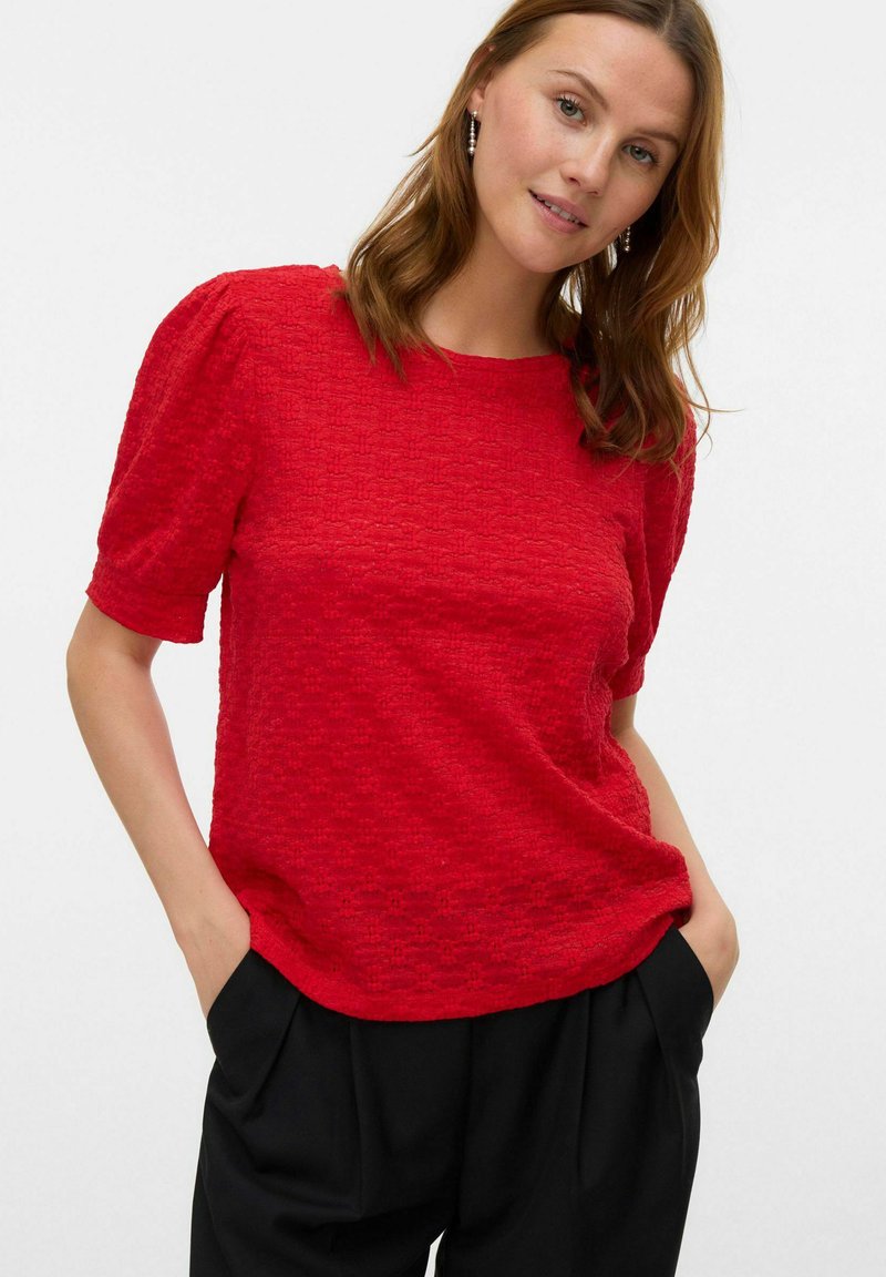 Top corto a maniche corte rosso con texture, collo rotondo e maniche a palloncino, abbinato a pantaloni neri larghi.