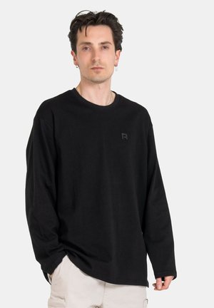 Black long-sleeve T-shirt made of cotton, featuring a crew neckline and a small tonal logo on the chest. Simple design, relaxed fit.
