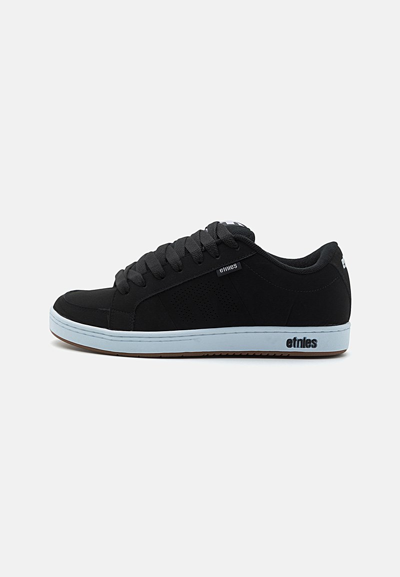 Sneakers pretas com um acabamento liso em camurça, bico arredondado, design de atacador, detalhes perforados nas laterais e uma sola de borracha branca em contraste.