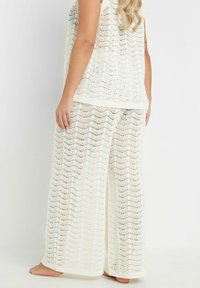 Conjunto de top sin mangas de ganchillo blanco y pantalones de pierna ancha, con un patrón en zigzag, textura ligera y bordes acanalados, diseñado para la comodidad.