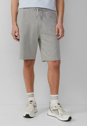 Graue Baumwollmischung-Shorts mit elastischem Bund und Kordelzug, ausgestattet mit Seitentaschen, kombiniert mit weißen Sneakern und gestreiften Socken.