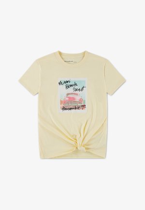 Κίτρινο βαμβακερό t-shirt με δέσιμο στο μπροστινό μέρος, με γραφικό σχέδιο ενός vintage αυτοκινήτου και κείμενο που γράφει «Miami Beach Sunset».