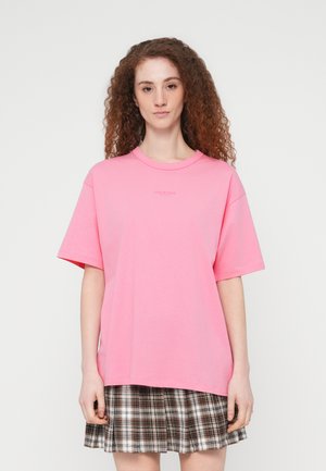 Rosa bomull t-skjorte med korte ermer og rund hals, med en subtil logo i midten. Kombinert med et rutete skjørt.