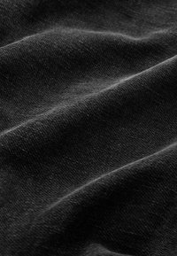 Black fabric with a soft, textured surface, featuring smooth, undulating folds and a subtle sheen, displaying fine, woven detail.