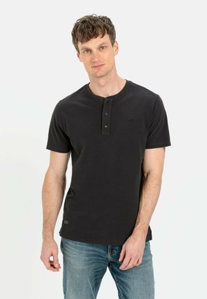 Schwarzes Kurzarm-Henley-Shirt mit Dreiknopfverschluss, strukturiertem Material und kleinem Logodetail. Tragen mit blauen Jeans.