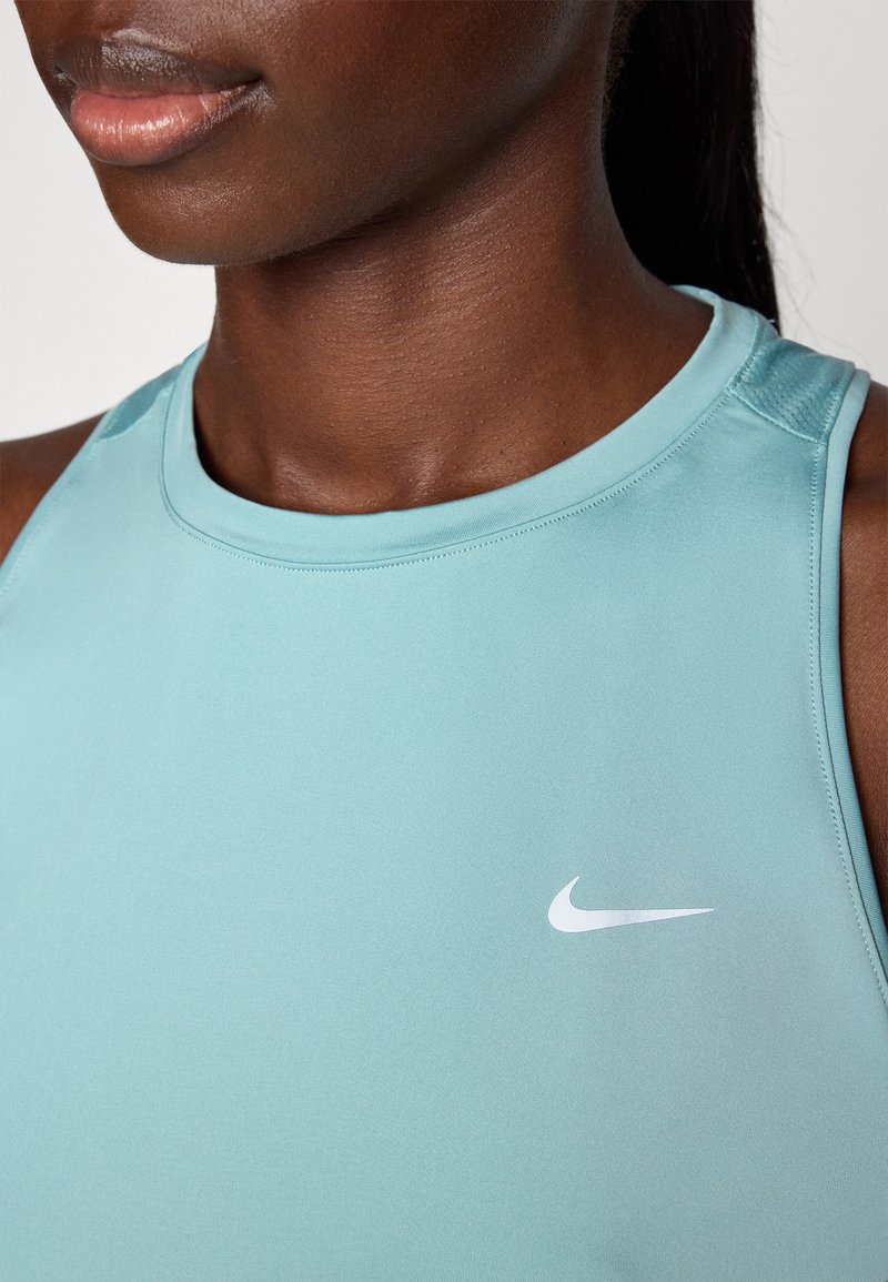 Un primer plano de una camiseta deportiva de Nike de color azul claro con un escote redondo y un pequeño logo de swoosh blanco en el lado izquierdo. Textura suave.