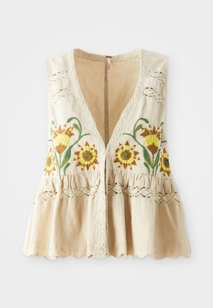Beige sleeveless blouse with floral embroidery in yellow and green, lace accents on shoulders, and a ruffled hemline. V-neck design.
