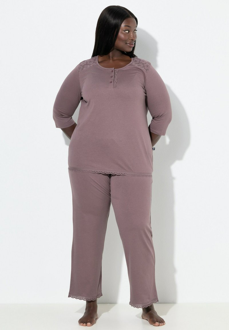 Jemná mauve pyžamo sestava obsahující top s tříčtvrtečním rukávem, zapínáním na knoflíky a krajkovými detaily, doplněná o odpovídající kalhoty s krajkovým lemem.