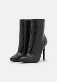 Czarne botki za kostkę o smukłym, spiczastym nosku i wysokim obcasie w szpilkę, z teksturowanym wzorem wężowym oraz zamkiem błyskawicznym po boku.