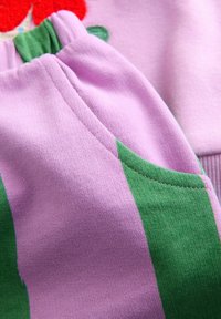 Purple cotton fabric with green accents, featuring a textured finish. Includes a gathered waistband and side pocket detail.