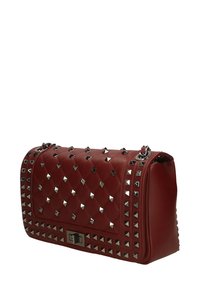 Borsa a tracolla rossa trapuntata con borchie a piramide argentate, accessori metallici e chiusura rettangolare. Texture liscia con una forma strutturata, incluso il manico per la spalla.