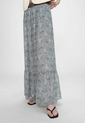 Jupe maxi fluide à motif cachemire bleu et gris, portée avec une ceinture marron et des sandales noires à bout carré sur un fond clair.