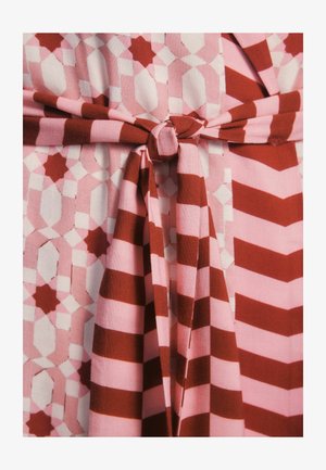 Mønstret stof har vekslende pink og røde geometriske former med en bundet talje detalje. Trykket inkluderer striber og former.