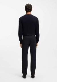 Granatowy dziany sweter i czarne spodnie, zaprojektowane z dopasowaną sylwetką, długimi rękawami, okrągłym dekoltem i gładką teksturą.