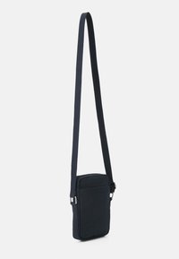 Námorní modrá crossbody taška vyrobená z odolné látky, s obdélníkovým tvarem, nastavitelným popruhem, přední kapsou a minimalistickým designem.