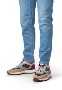 Sneakers con un mix di camoscio e rete nei colori beige, marrone, grigio e blu. Suola spessa con battistrada testurizzato; dettagli di lacci e branding in evidenza.