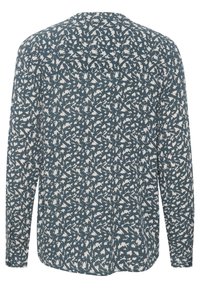 Blouse à manches longues en teal foncé avec un motif abstrait blanc, en tissu léger, avec un ourlet arrondi et un détail de patte de boutonnage au dos.
