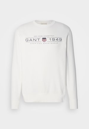 Weißer Sweatshirt mit langen Ärmeln, Rundhalsausschnitt und gerippten Bündchen. Enthält den Text "GANT 1949" sowie ein Logo in Dunkelblau und Rot.