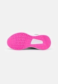 Semelle de chaussure avec un motif texturé rose vif, une section médiane blanche et des détails de semelle extérieure noirs, photographiée sur un fond blanc.