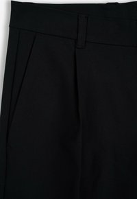 Czarne spodnie z tkaniny w plecionce, z płaskim przodem, z zakładkami, solidnym paskiem w talii i bez widocznych elementów metalowych.