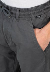 Pantalones cortos grises de algodón con cinturilla elástica y cordón. Presenta bolsillos laterales y detalles de costura sutiles.