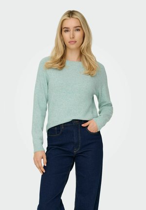 Lichtgroene gebreide trui met een ronde hals en lange mouwen, gecombineerd met donkerblauwe high-waisted denim jeans. Glad textuur, casual pasvorm.