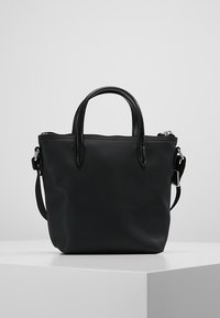 Bolsa tote negra texturizada con cierre de cremallera, doble asa superior, correa de hombro desmontable y diseño minimalista.
