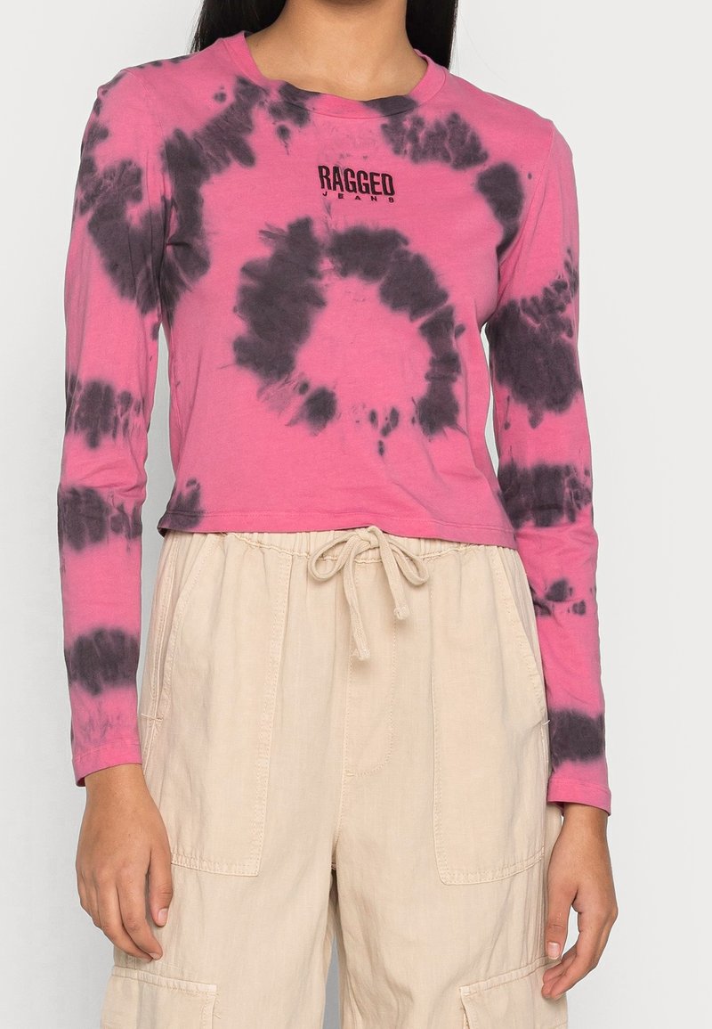 Long-sleeve, pink tie-dye shirt with black swirl patterns and "RAGGED" logo on the chest, paired with light beige drawstring pants.