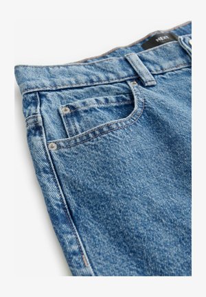 Keskmise sinise värvusega denim jeanid, millel on tuhm tekstuur. Omadusteks on viis taskut, vaskkinnitusdetailid ja õmblused külgedel.