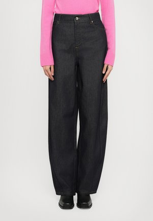 Jeans en denim foncé à jambes larges et taille haute, avec une fermeture à bouton et des coutures contrastantes. Associés à un pull rose vif.