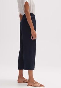 Námořnické modré zkrácené kalhoty se střihom do rovna a elastickým pasem. V sadu s lehkým, strukturovaným bílým topem a plochými sandály.