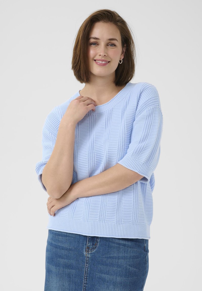 Light blue knit sweater with ribbed texture and short sleeves. Paired with a denim skirt. Simple round neckline.