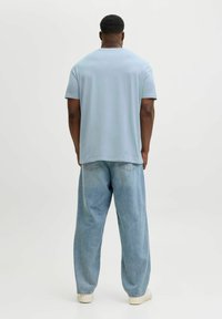 Lyseblå kortærmet t-shirt med afslappet pasform. Kombineret med løstsiddende, lyse denimjeans. Minimalistisk design, glat tekstur og enkel konstruktion.