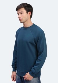 Felpa blu navy con collo a giro, maniche raglan e polsini a costine. Realizzata in un tessuto testurizzato, presenta un taglio morbido.