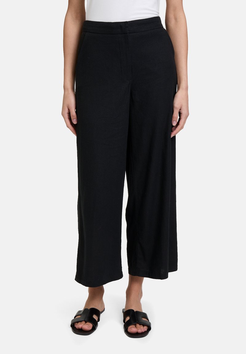 Zwarte wijde broek met een gladde textuur en een hoge tailleband, die is voorzien van discreet zijzakken en is gecombineerd met open-toed zwarte sandalen.