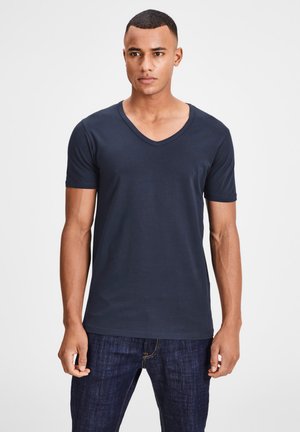 Navy blue v-neck t-shirt made of soft cotton, featuring short sleeves, a fitted shape, and a smooth texture. Worn with dark jeans.