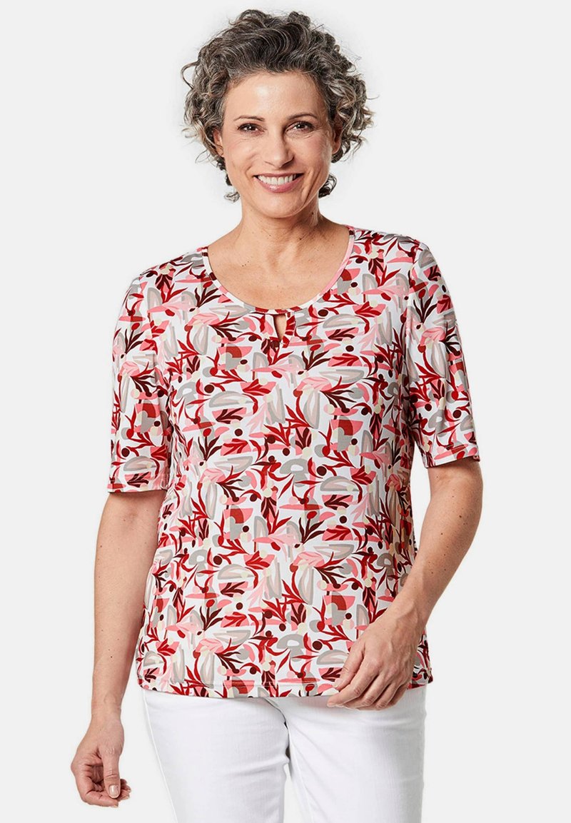 Korte mouwen top met een ronde halslijn, voorzien van een roze bloemenpatroon op een lichte achtergrond en een klein sleutelgaatje detail bij de nek.