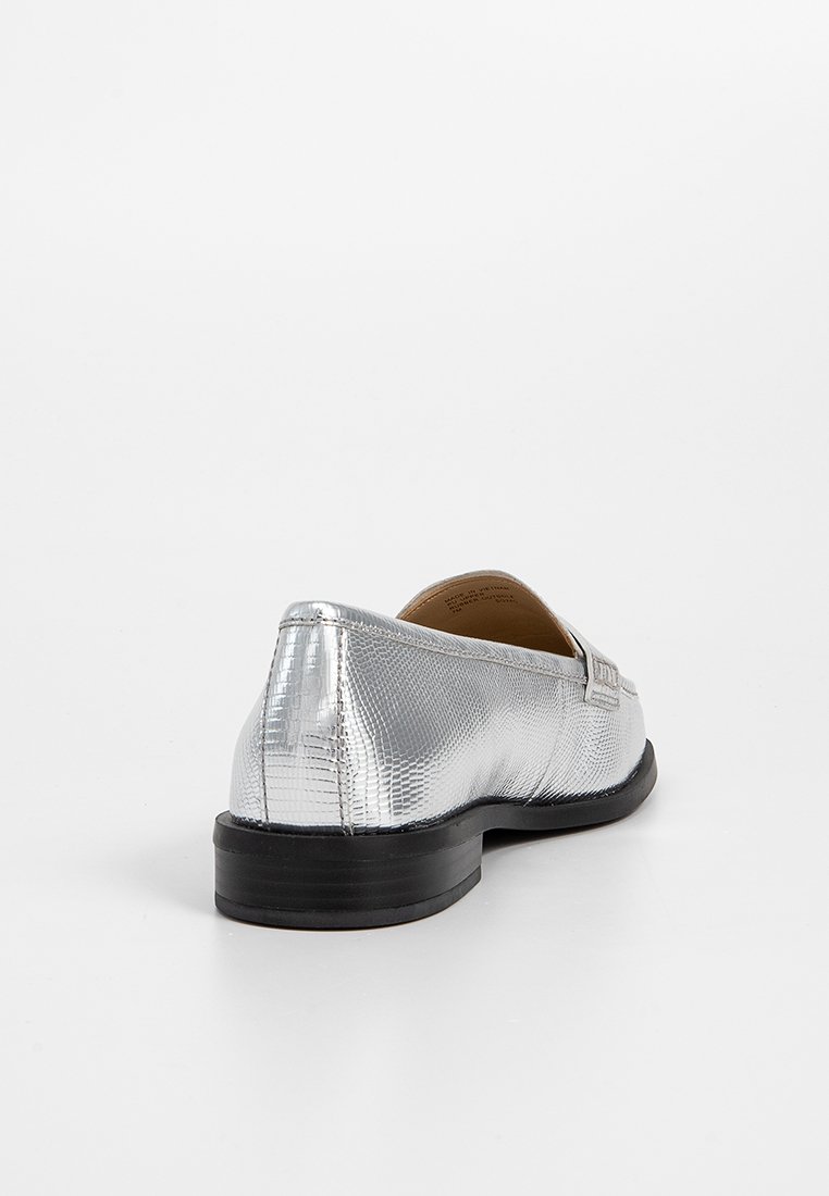 Mocassin argenté, texturé, au design épuré, avec une semelle noire plate et des détails de coutures subtiles. La vue arrière montre une finition lisse.
