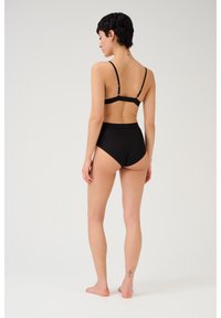 Set di reggiseno nero e mutandine a vita alta con spalline regolabili, tessuto morbido e design minimalista. Nessun motivo visibile o dettagli hardware.
