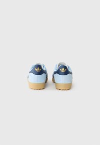 Blå semskede sneakers med en marineblå hælkappe og tre sorte striber. Gummisål med en struktureret overflade; guld logo accent på hælen.