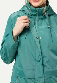 Teal waterdichte jas met hoge kraag, ritssluiting aan de voorkant, verstelbare trekkoorden en drukknoopsluiting.